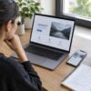 A digital marketer reviews a landing page on a laptop and smartphone while planning page improvements